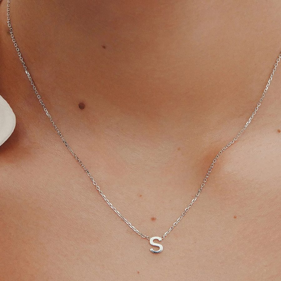 Close-up of a person wearing Sarah & Sebastian’s The Letter Necklace in the letter S.