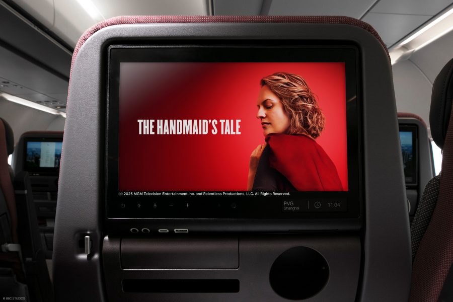 A seatback screen on a Cathay Pacific plane shows a red and white promotional image for The Handmaid’s Tale