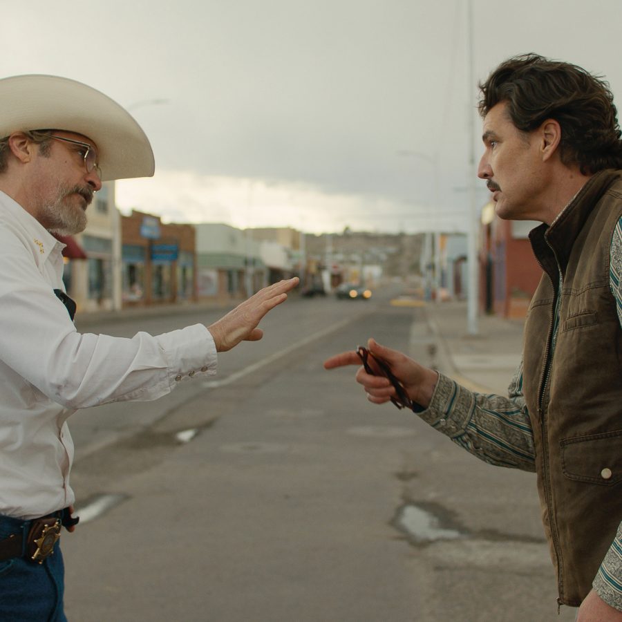 Two men argue on a rural town street in a scene from Eddington.