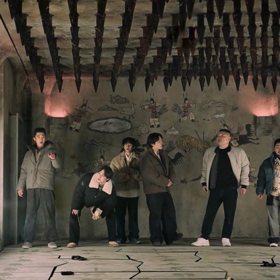 A group of men nervously look around a room that has drawings on the walls and floor and spikes on the ceiling, in The Great Escape: The Story