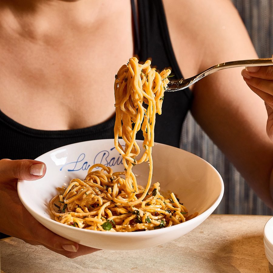 A person lifting up a forkful of pasta at La Baia in Hong Kong.