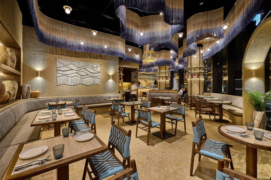 The blue and cream interiors of La Baia with fringed ombre decorations and tables laid out.