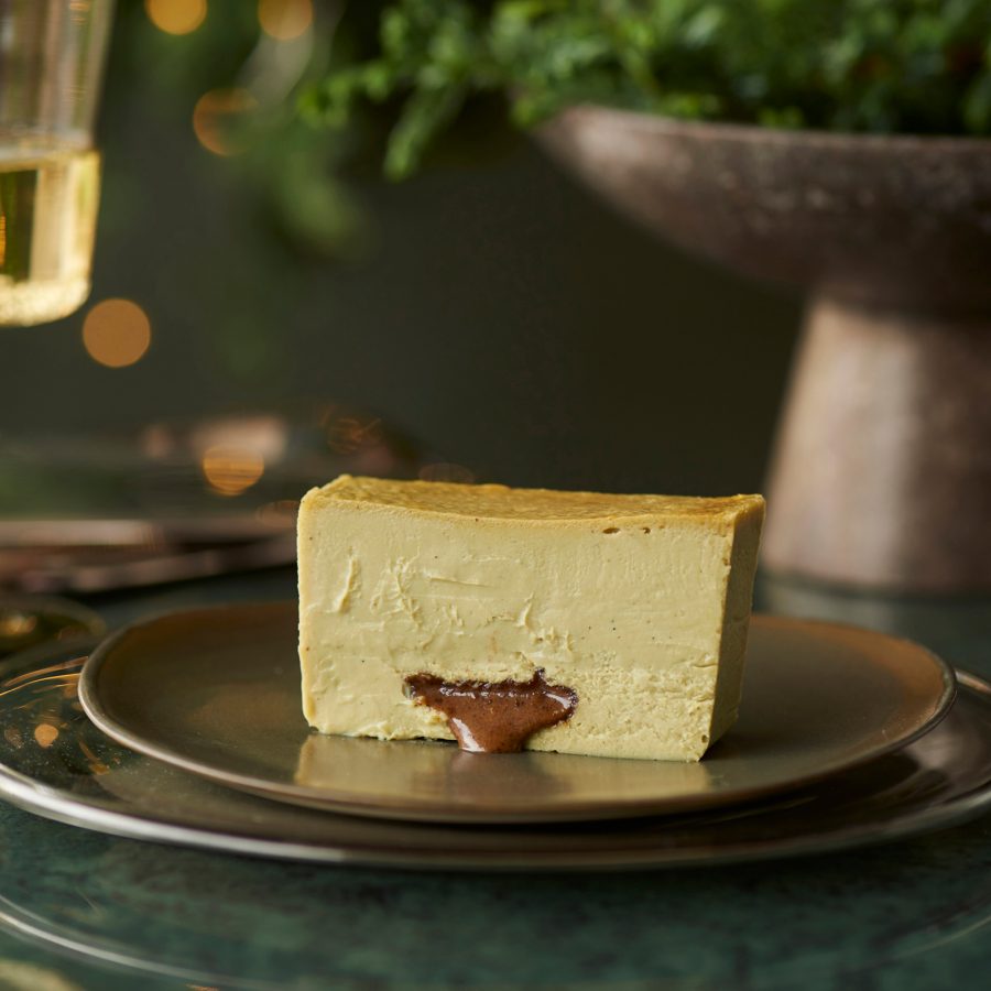 A wedge of cheesecake served at Mr. Cheesecake with a glass of wine in the background.