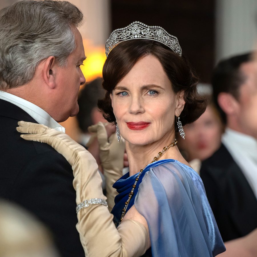 A woman in a ballgown stands amid a crowd of elegant guests at a party, in a scene from Downton Abbey: The Grand Finale