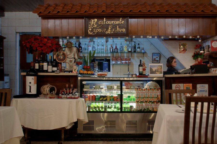 The interior of Restaurante Espaço Lisboa showcasing European-style décor, wine bottles, and a chilled drinks display behind the counter.