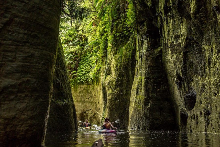 Two people kayak through a canyon in New Zealand.