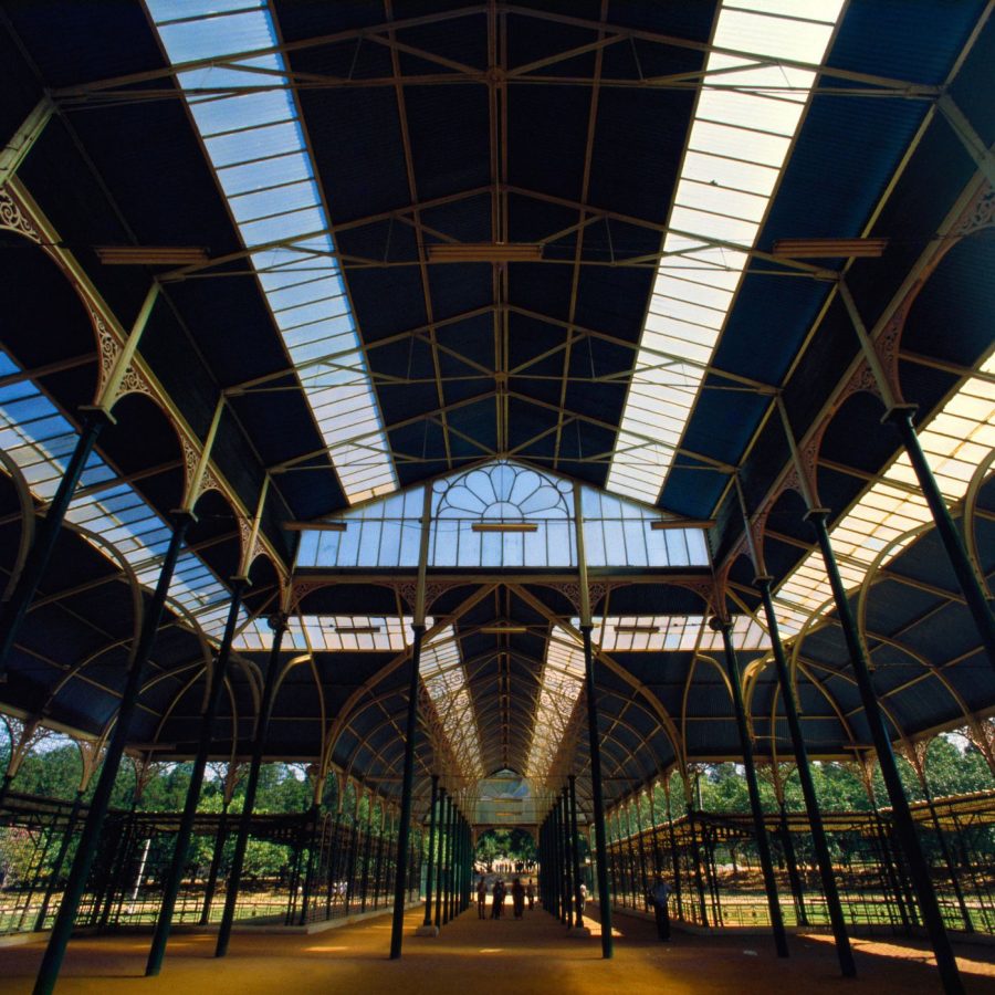 Glasshouse surrounded by lawns and mature trees at Lalbagh Botanical Garden in Bengaluru