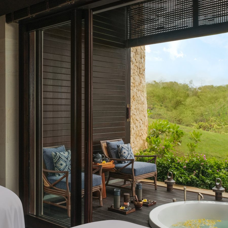 A luxury spa suite at Raffles Bali featuring a bathtub and open-air balcony overlooking the hillside.