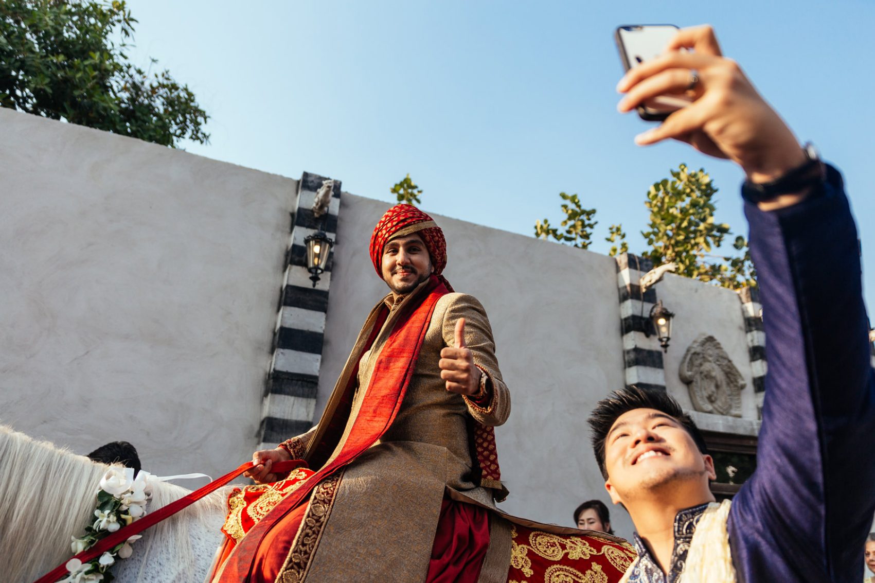 An indian groom on a horse with a man talking a selfie. Credit: 123RF