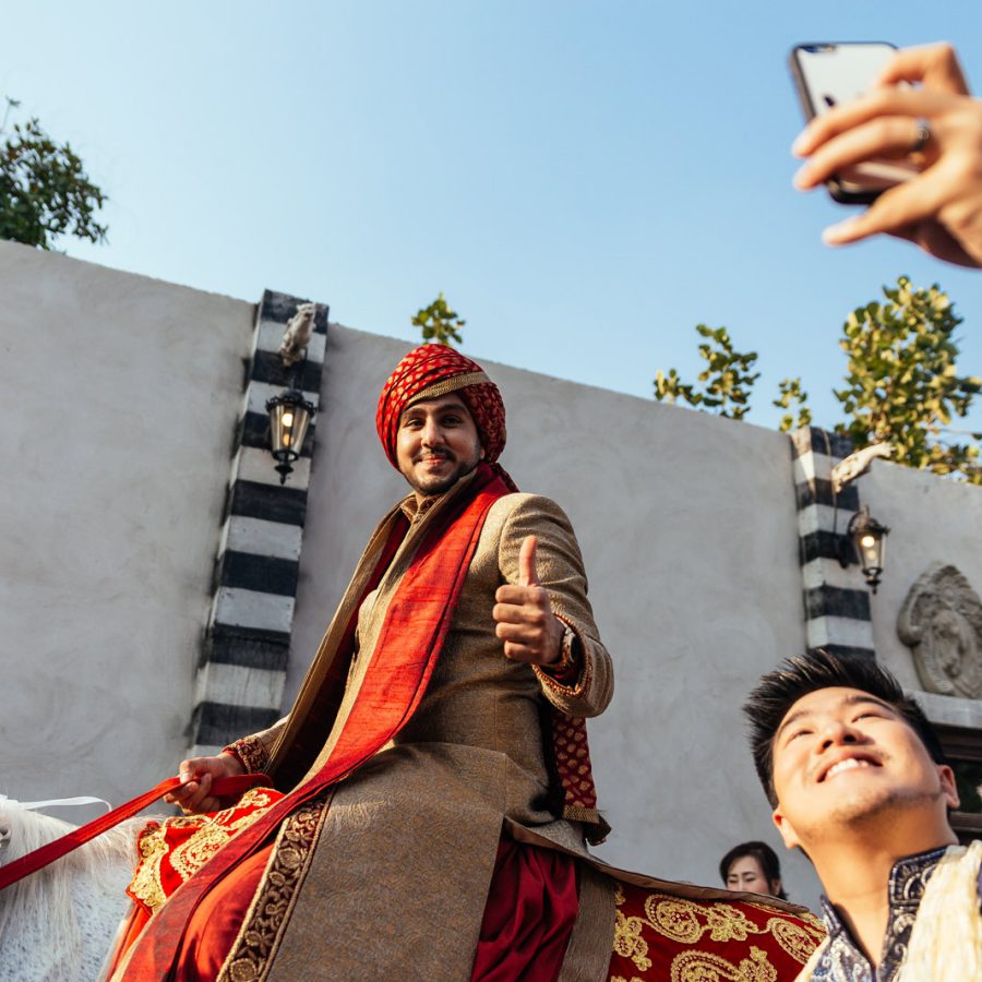 An indian groom on a horse with a man talking a selfie. Credit: 123RF