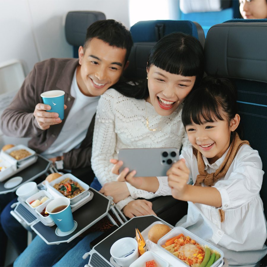 A young Asian family on a Cathay Pacific flight enjoying a meal and taking a selfie