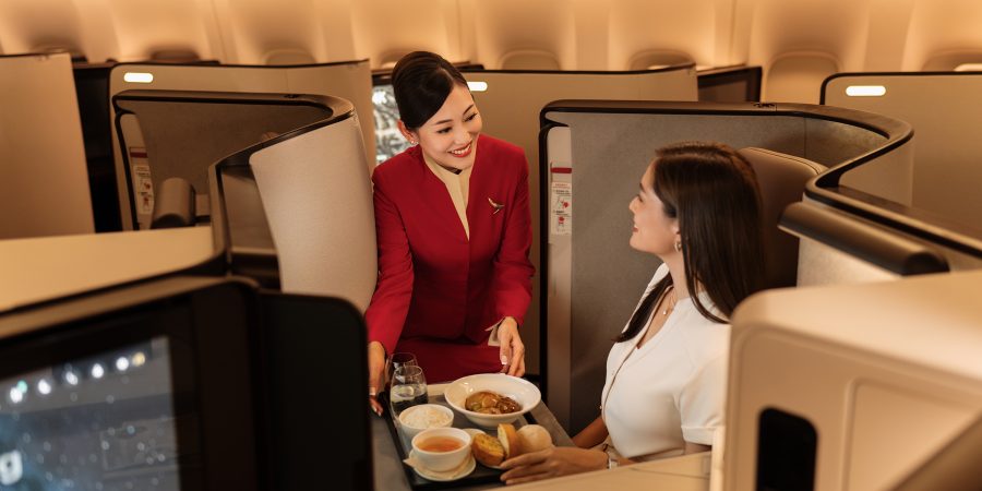 A Cathay Pacific cabin crew offers an inflight meal to a female passenger seated in Business class 