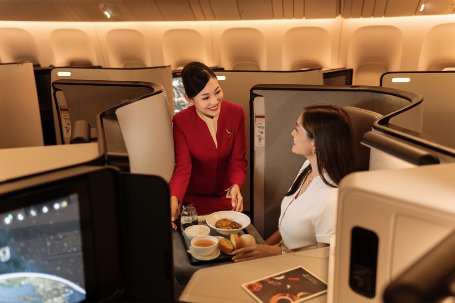 A Cathay Pacific cabin crew offers an inflight meal to a female passenger seated in Business class.
