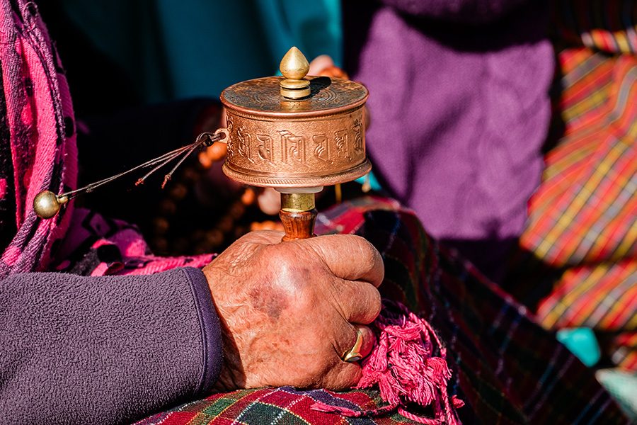 One hand holds a Bhutanese folklore item.