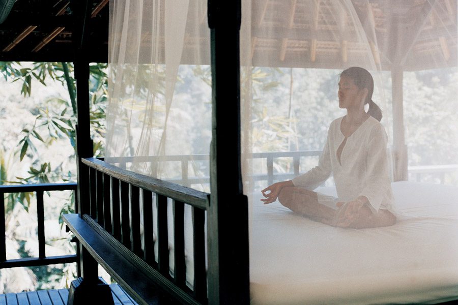 A woman meditating on a bed at Como Shambhala Estate