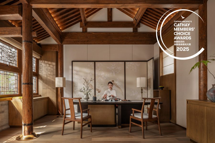 Woman pouring tea in an elegant Chinese hotel room with light streaming through the window.