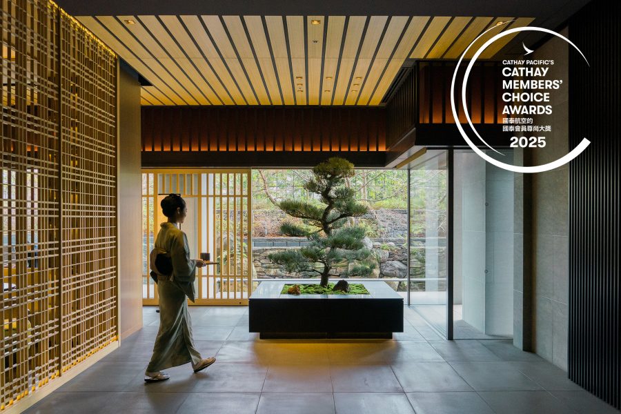 A woman dressed in a kimono carries a cup of tea by a bonsai tree at The Ritz-Carlton in Kyoto, Japan.