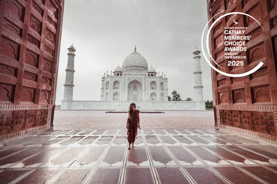 A woman in traditional Indian clothing standing in front of the Taj Mahal. 