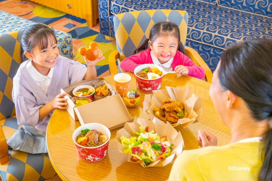 Two young girls with their mother eating a meal and looking happy at the Disney Ambassador Hotel, Tokyo, Japan