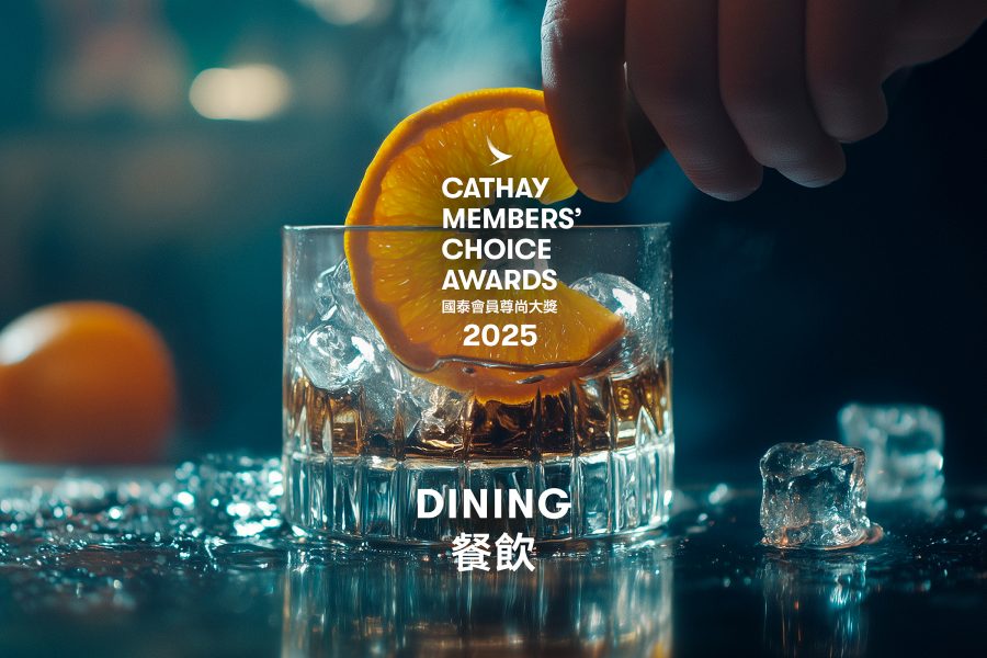 A closeup of a hand placing a slice of orange in a whisky glass with lock up of Cathay Membership Choice Awards 2025