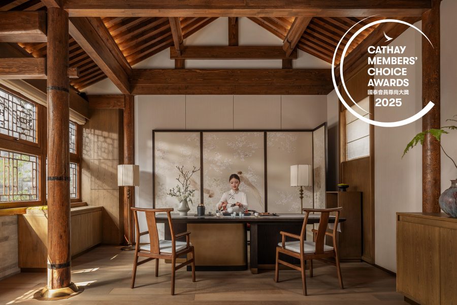Woman pouring tea in an elegant Chinese hotel room with light streaming through the window.