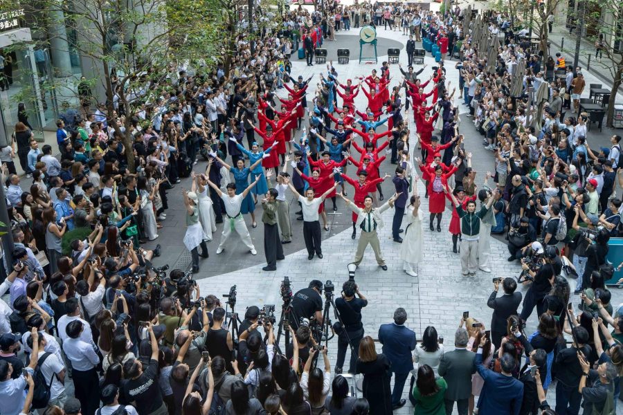 A choreographed dance performance celebrating Cathay's 80th anniversary, with performers in vintage uniforms and spectators lining both sides of the walkway.