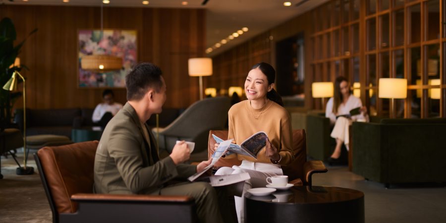 A woman elegantly enjoying afternoon tea at a restaurant while browsing exclusive offers on her Standard Chartered Cathay Mastercard.