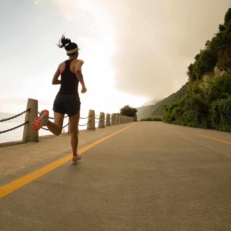 Lady running along the road beside the sea