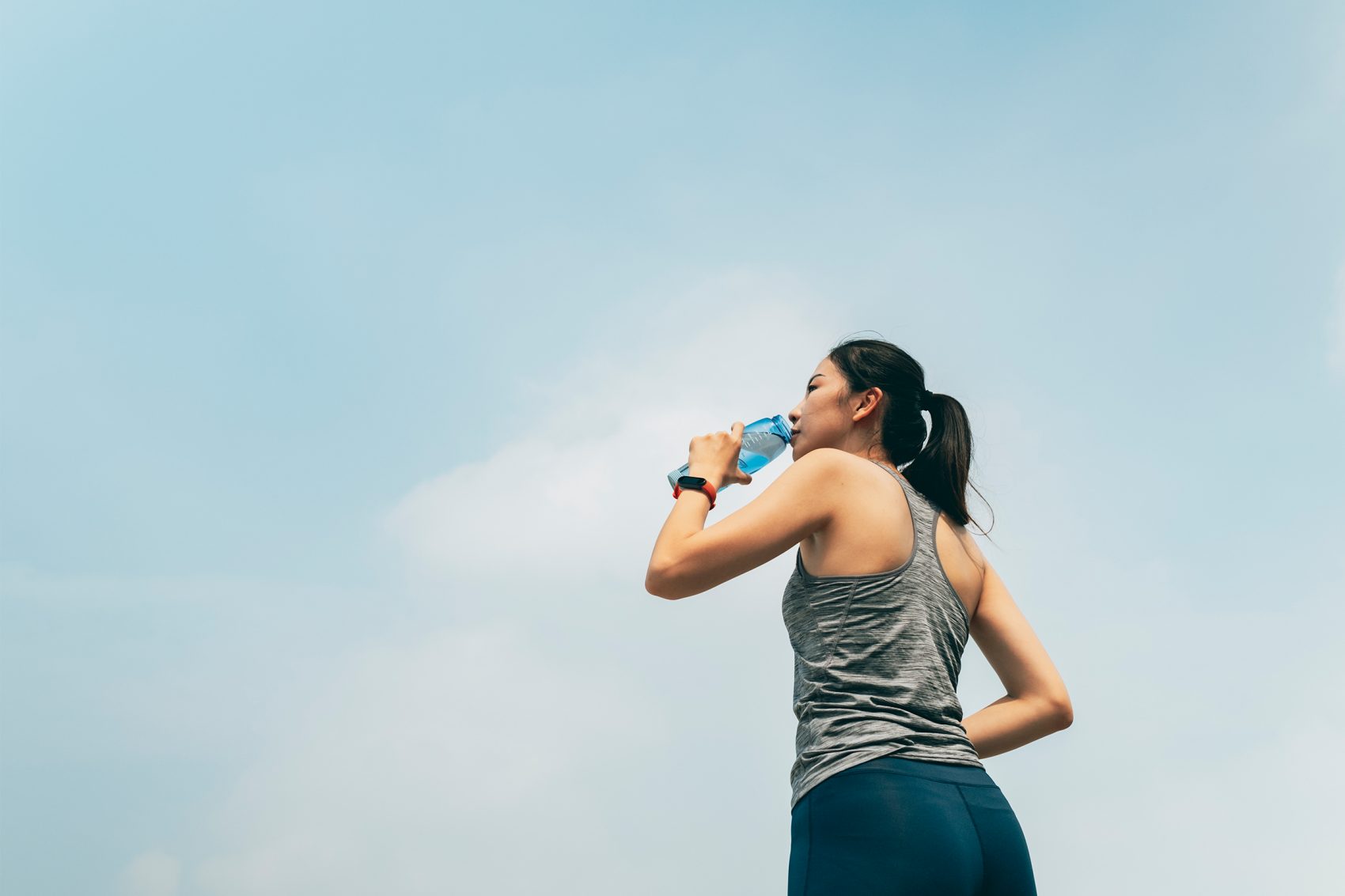 A female runner drinking water from a reusable water bottle