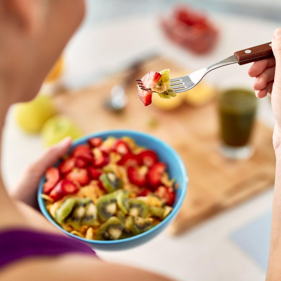 A person eating a bowl of mixed fruits