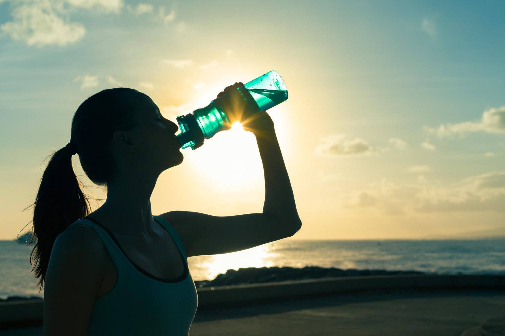 Silhouette of lady drinking from a reusable water bottle