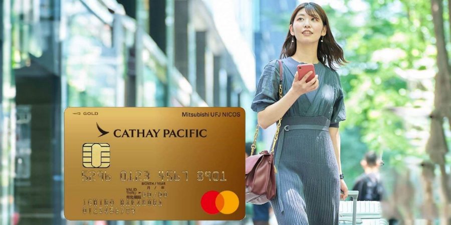 A hand holding a contactless  Standard Chartered Cathay co brand credit card with Cathay and Standard Chartered logos, and Mastercard logo.