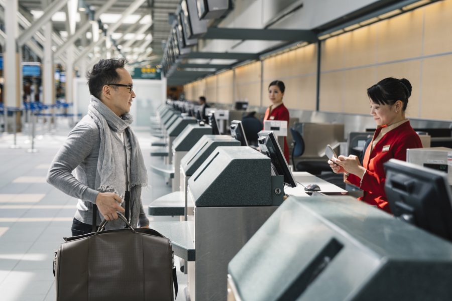 A passenger standing in front of the check-in counter and checking passport by the check-in staff.