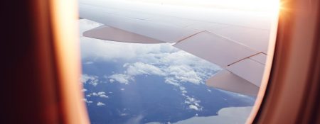 A view of an airplane wing and clouds below from the window seat of a Cathay Pacific aircraft.