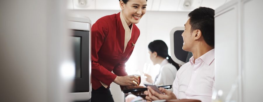 A cabin crew serving a bowl of fish ball noodles on a black tray. 
