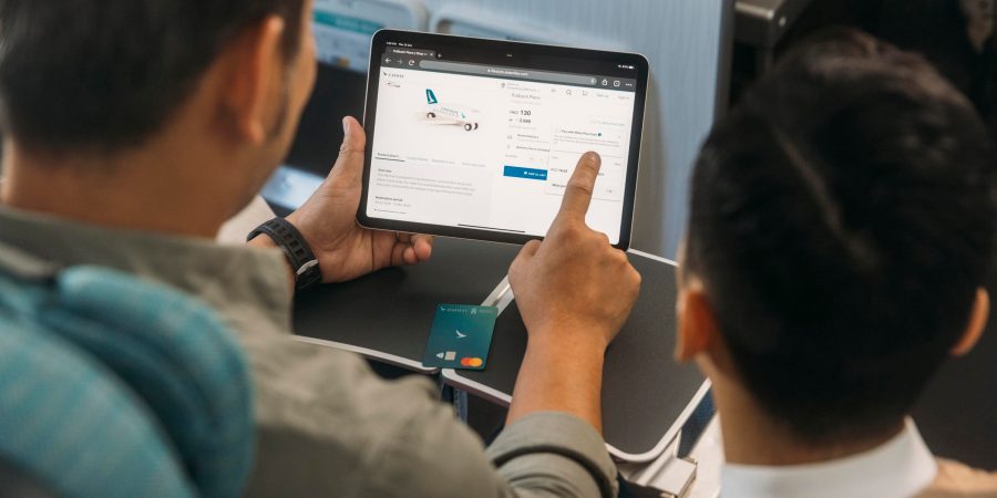 A person browsing Cathay Pacific's shopping site and pointing at a tablet with a credit card on the table