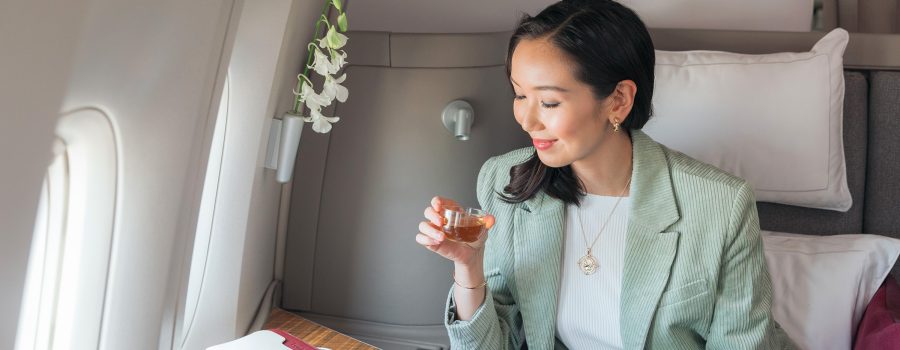 空中服务员为安坐国泰航空头等舱座位的乘客奉上香槟