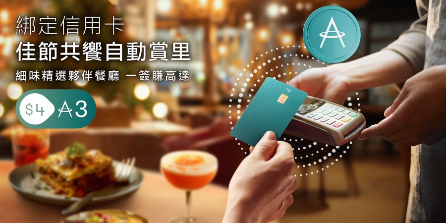 特寫在非接觸式支付終端機上使用信用卡的手。背景中，餐廳的桌上擺放著雞尾酒和意式千層麵。