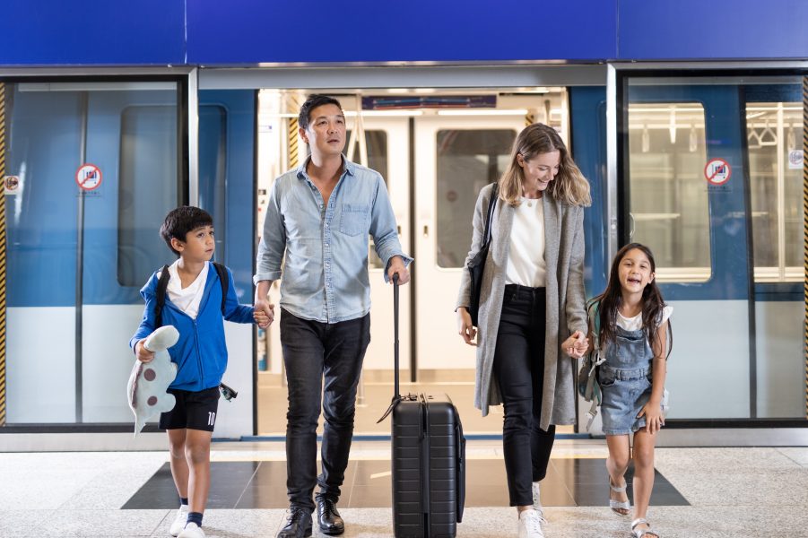 A family of four with two children getting off the automated people mover, HKIA's train shuttle. The children are holding their parents' hands.