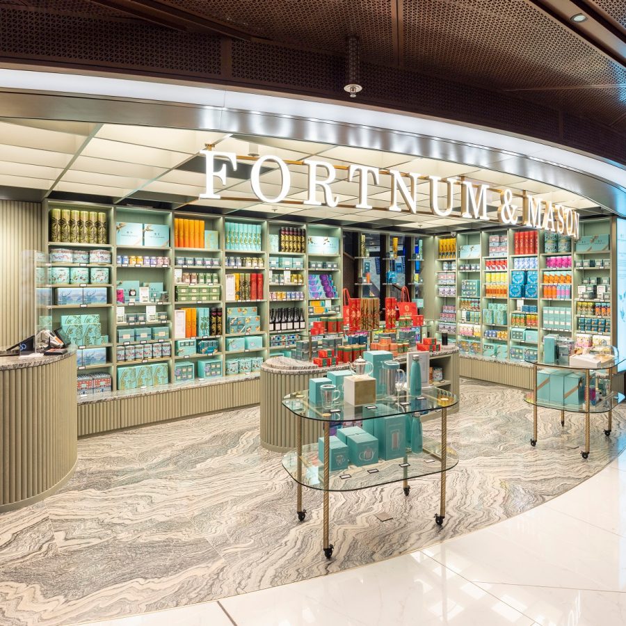 The storefront of Fortnum and Mason at Hong Kong International Airport. The interiors are decorated in yellow and gold furnishing, and large colourful tins are displayed.