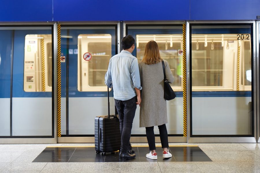 Back view of a couple waiting to board the automated people mover (APM) at Hong Kong International Airport.