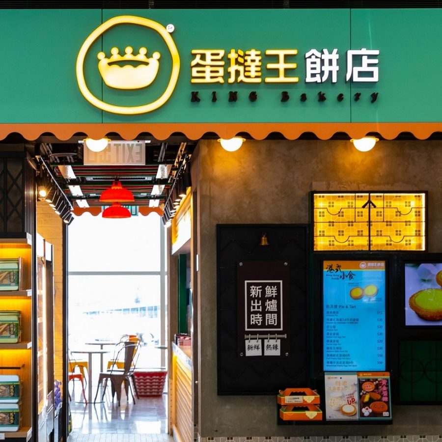 The shopfront of King Bakery with a large green sign. Several tables and seats can be seen inside the shop venue. 