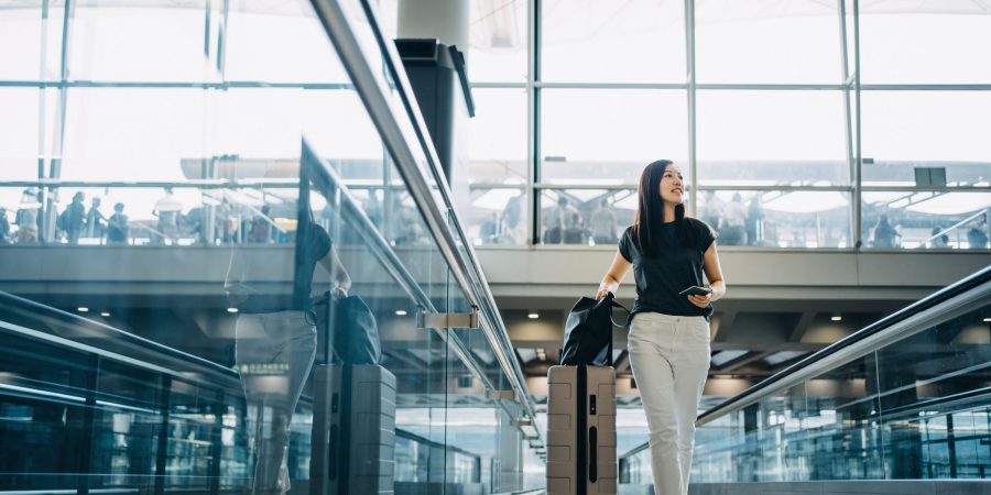 A lady in the airport carrying the luggage and ready for her trip with Standard Chartered Mastercard