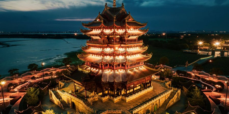 夜間燈光照亮南昌滕王閣，周圍環繞著園林與步道，背景為河流景致。